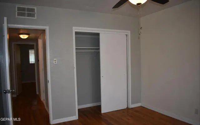 a view of an empty room with wooden floor and closet