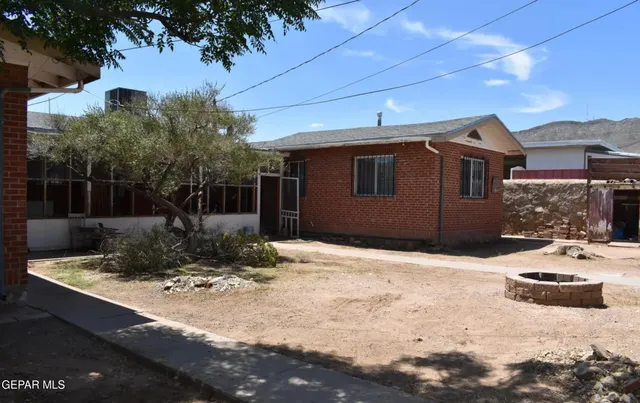 a view of a patio with a table and chairs under an umbrella with a fire pit