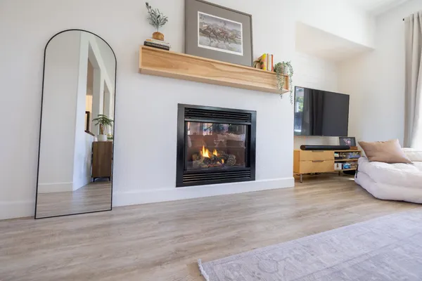 a view of living room kitchen with stainless steel appliances stove refrigerator and fireplace