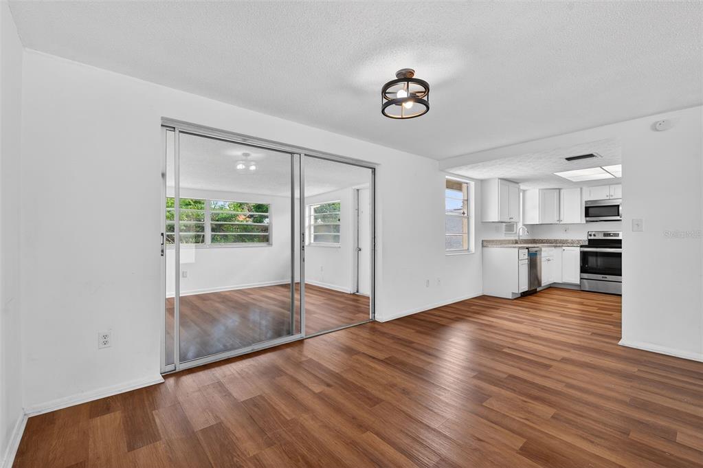 8626 Robilina Road Port Richey, FL 34668 - Photo 15 of 60 a view of empty room with wooden floor and kitchen view