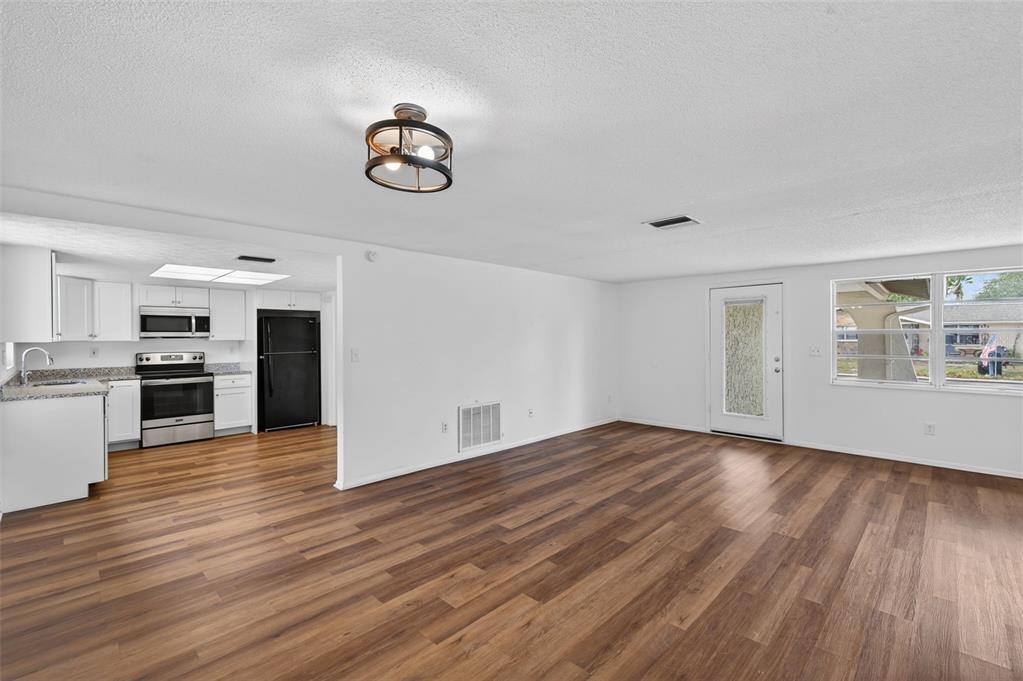 8626 Robilina Road Port Richey, FL 34668 - Photo 16 of 60 a view of kitchen and empty room with wooden floor
