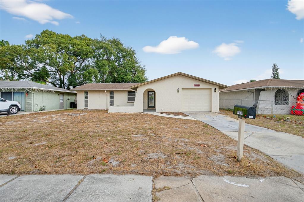 8626 Robilina Road Port Richey, FL 34668 - Photo 4 of 60 a front view of a house with a yard and garage
