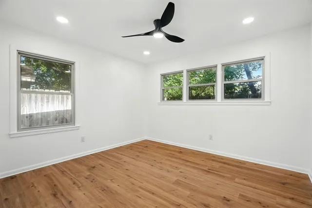 a view of empty room with wooden floor and fan