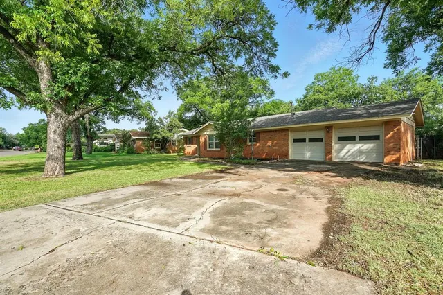 a backyard of a house with large trees and plants