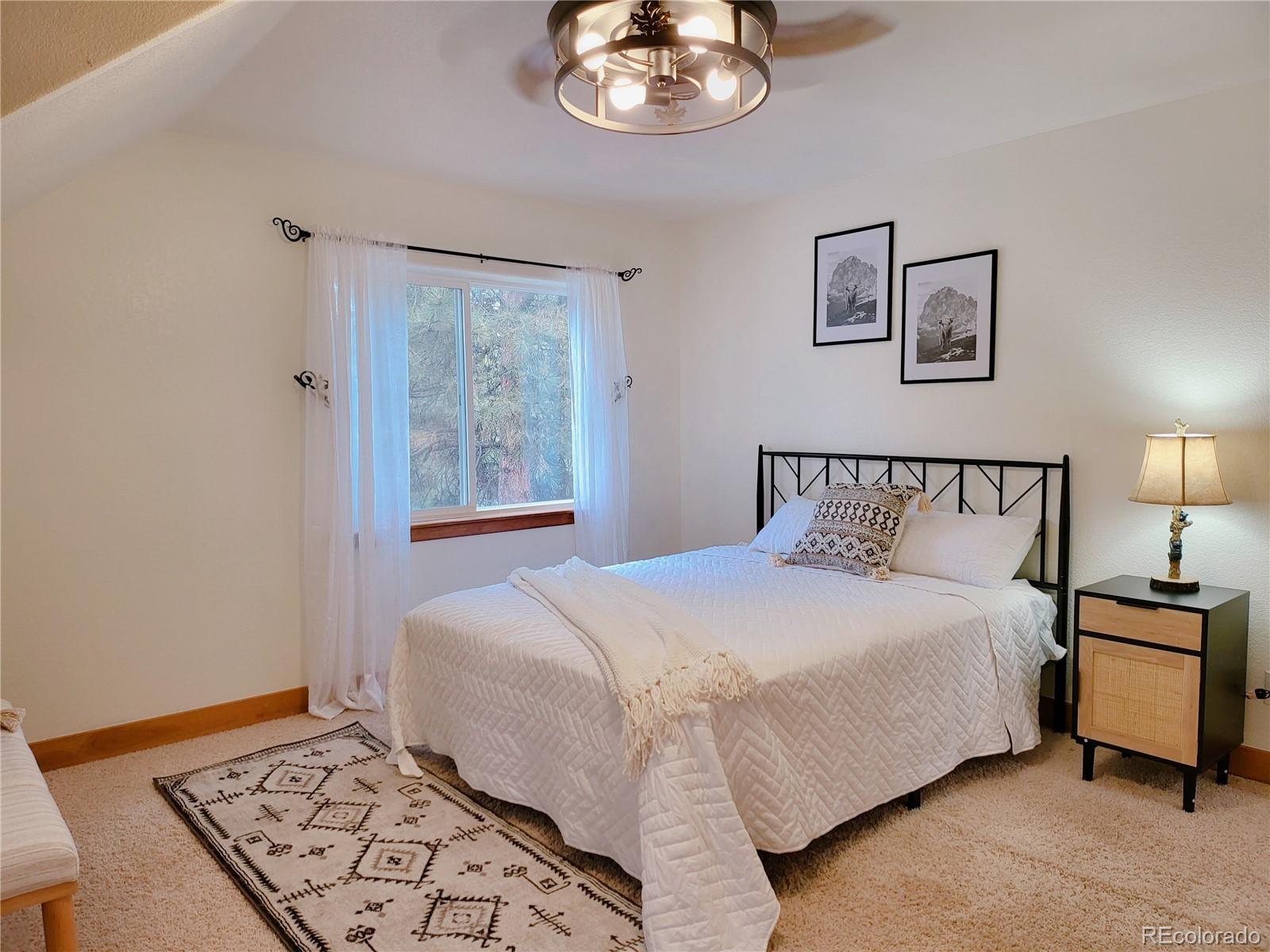 20133 Silver Ranch Road Conifer, CO 80433 - Photo 20 of 40 a bedroom with a bed and a lamp on dresser