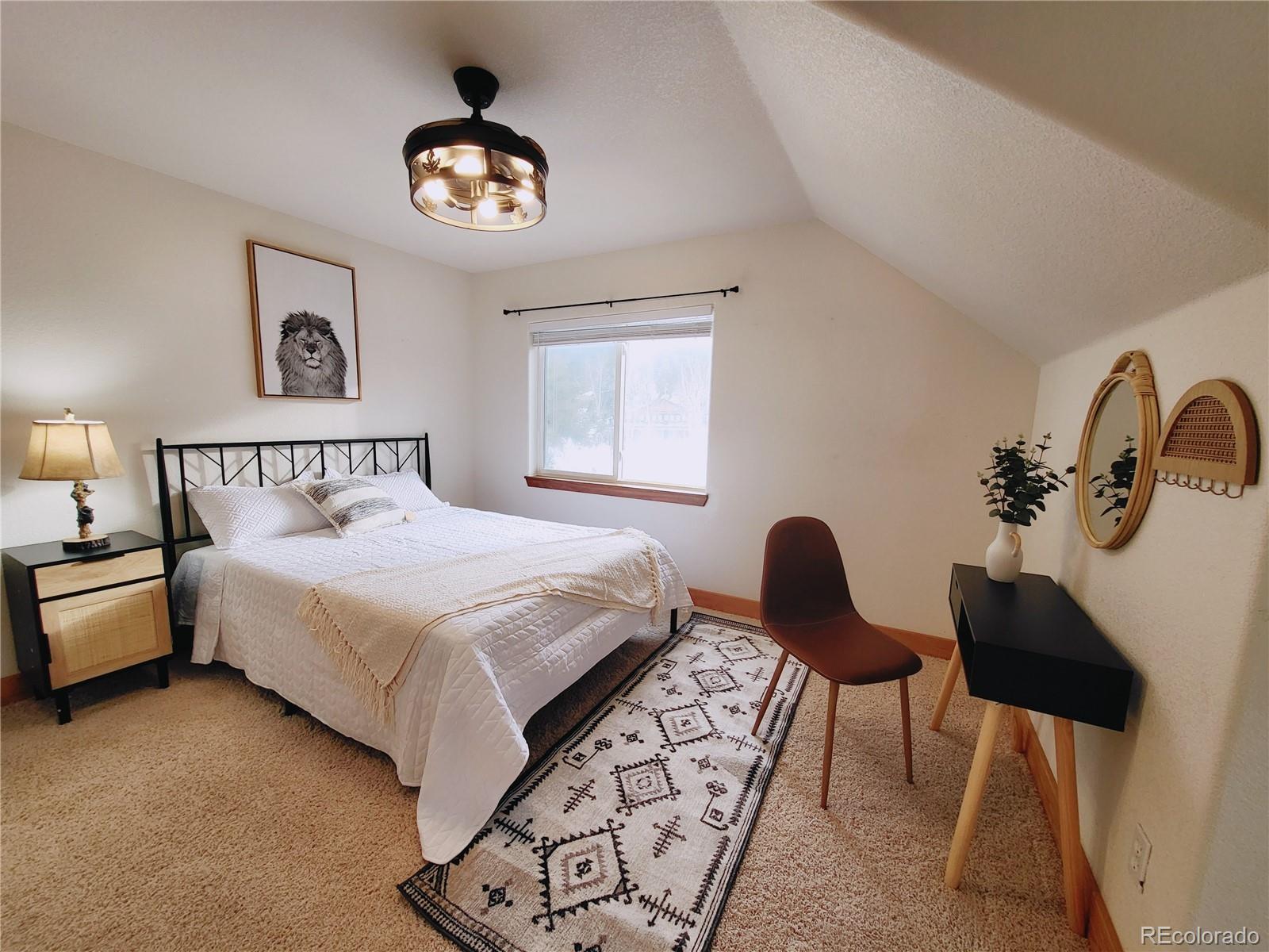 20133 Silver Ranch Road Conifer, CO 80433 - Photo 22 of 40 a bedroom with a bed and a chandelier