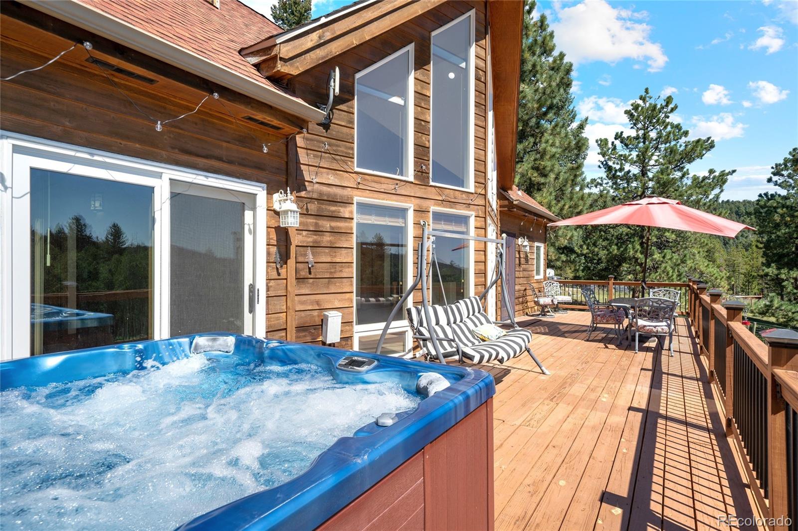 20133 Silver Ranch Road Conifer, CO 80433 - Photo 35 of 40 a view of a patio with a table and chairs under an umbrella with wooden floor