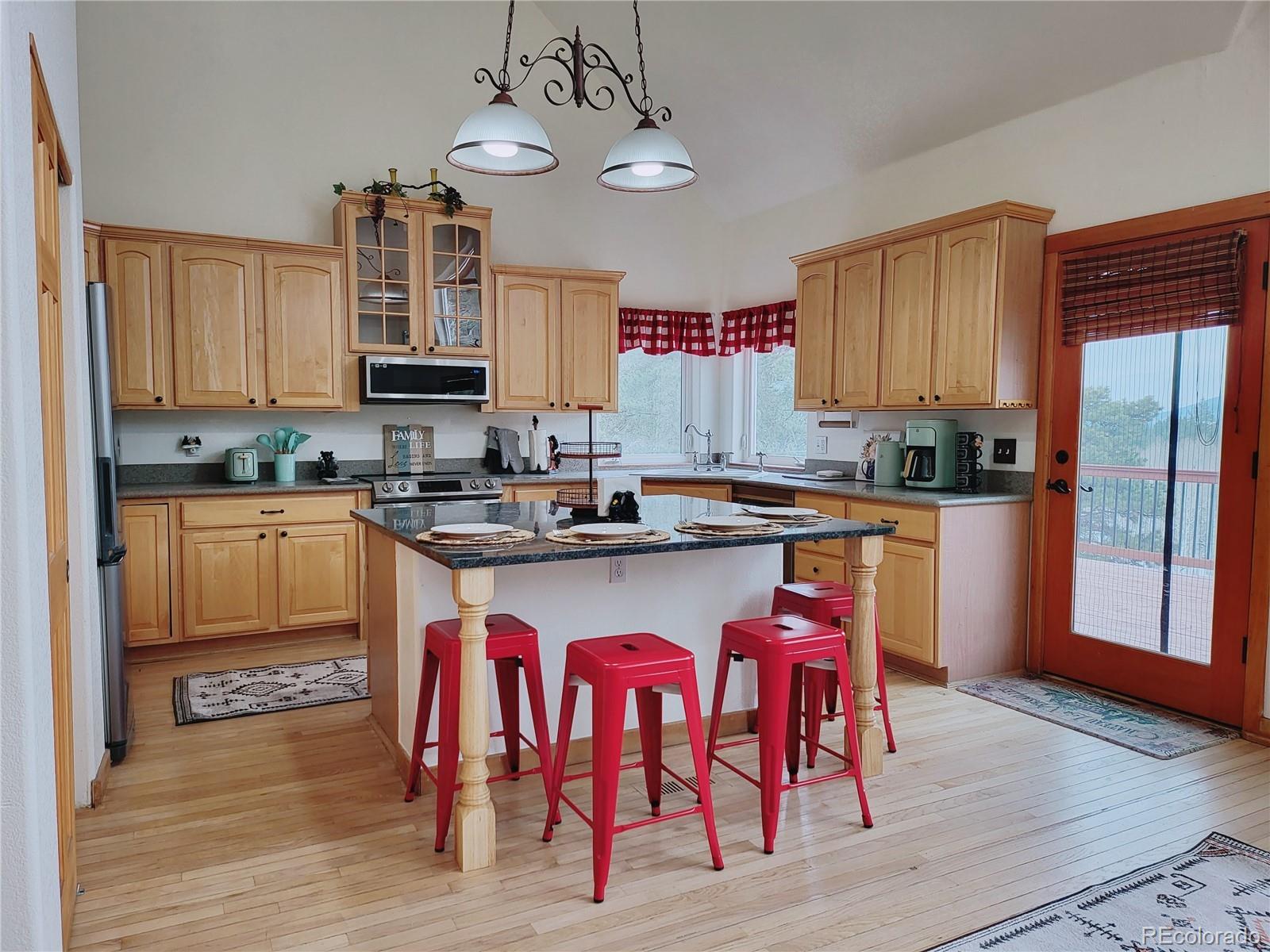 20133 Silver Ranch Road Conifer, CO 80433 - Photo 5 of 40 a kitchen with stainless steel appliances granite countertop a sink dishwasher a stove a refrigerator with a dining table and chairs with wooden floor
