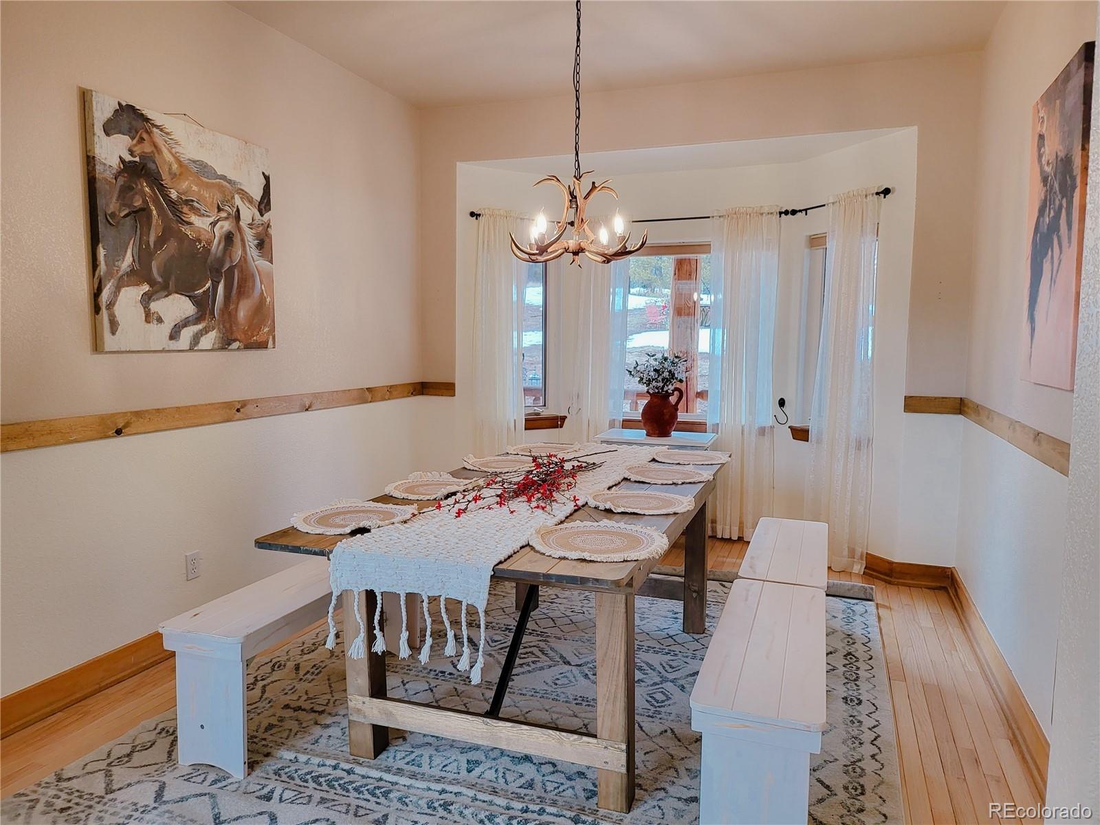 20133 Silver Ranch Road Conifer, CO 80433 - Photo 8 of 40 a view of a dining room with furniture a chandelier and wooden floor