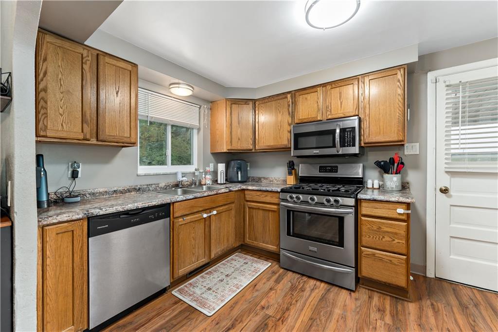 3905 Middleboro Road Pittsburgh, PA 15234 - Photo 10 of 32 a kitchen with stainless steel appliances granite countertop wooden cabinets a stove a sink and dishwasher with wooden floor
