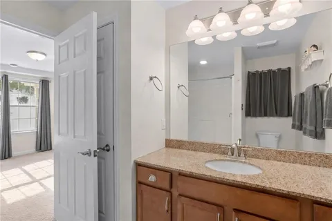 a bathroom with a granite countertop sink a large mirror and a shower