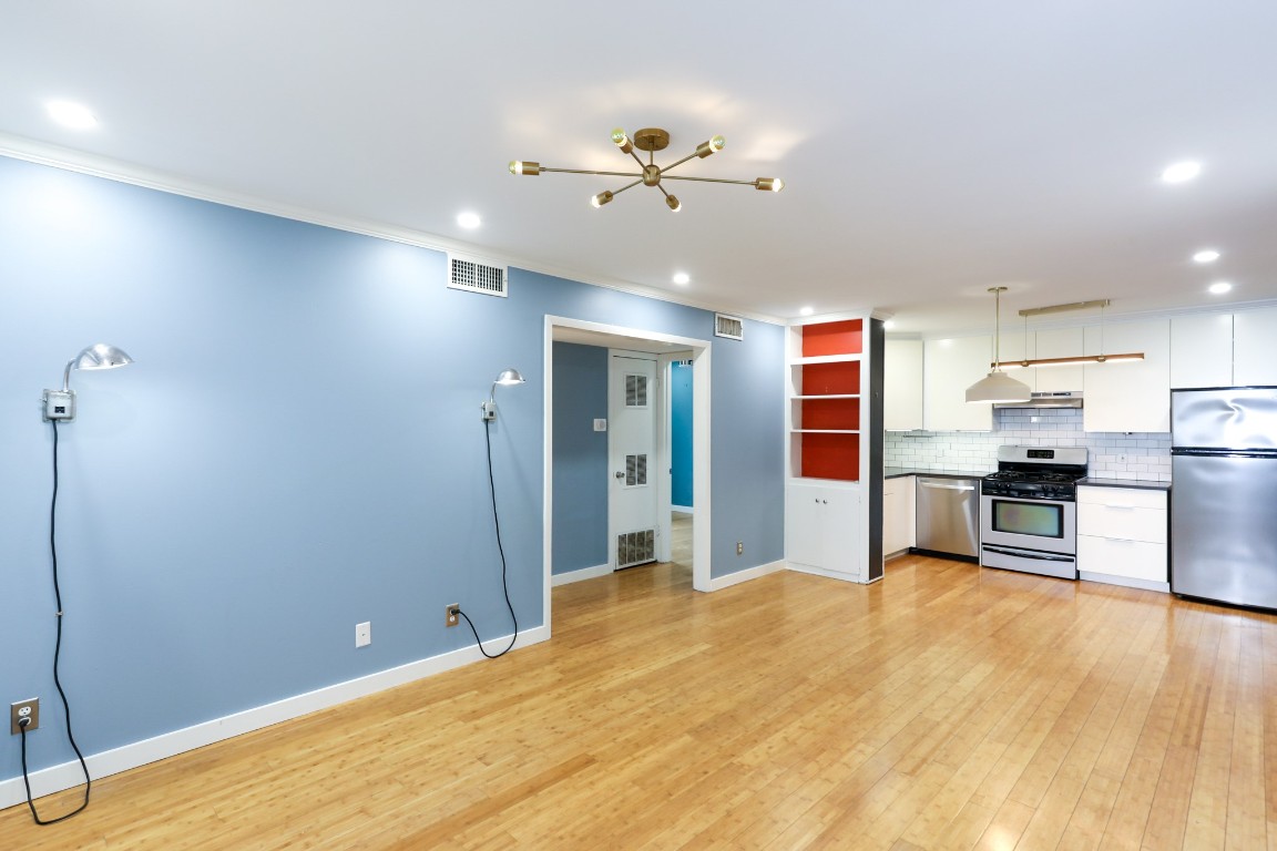 1304 Summit Street, Unit 209 Austin, TX 78741 - Photo 2 of 27 a room with kitchen island stainless steel appliances cabinets and wooden floor