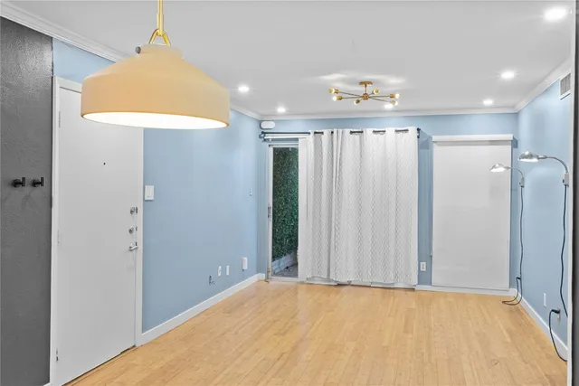 a room with kitchen island stainless steel appliances cabinets and wooden floor