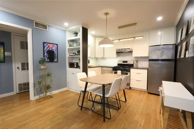 a kitchen with stainless steel appliances granite countertop a refrigerator a microwave a stove and a dining table with wooden floor