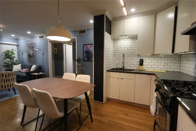 a kitchen with stainless steel appliances granite countertop wooden floor sink stove dining table and chairs