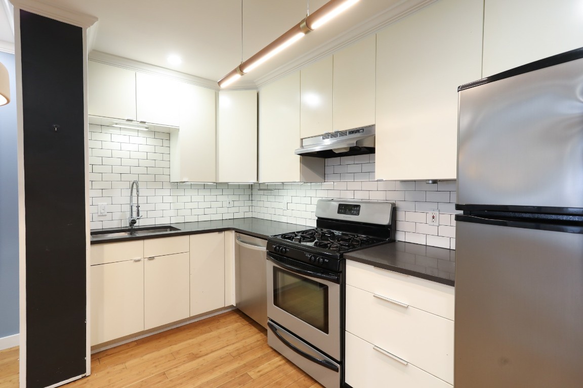 1304 Summit Street, Unit 209 Austin, TX 78741 - Photo 7 of 27 a kitchen with stainless steel appliances granite countertop a stove a sink and a refrigerator