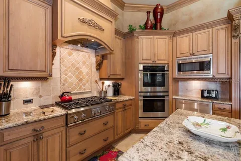a kitchen with stainless steel appliances granite countertop a stove a sink dishwasher and microwave with wooden cabinets