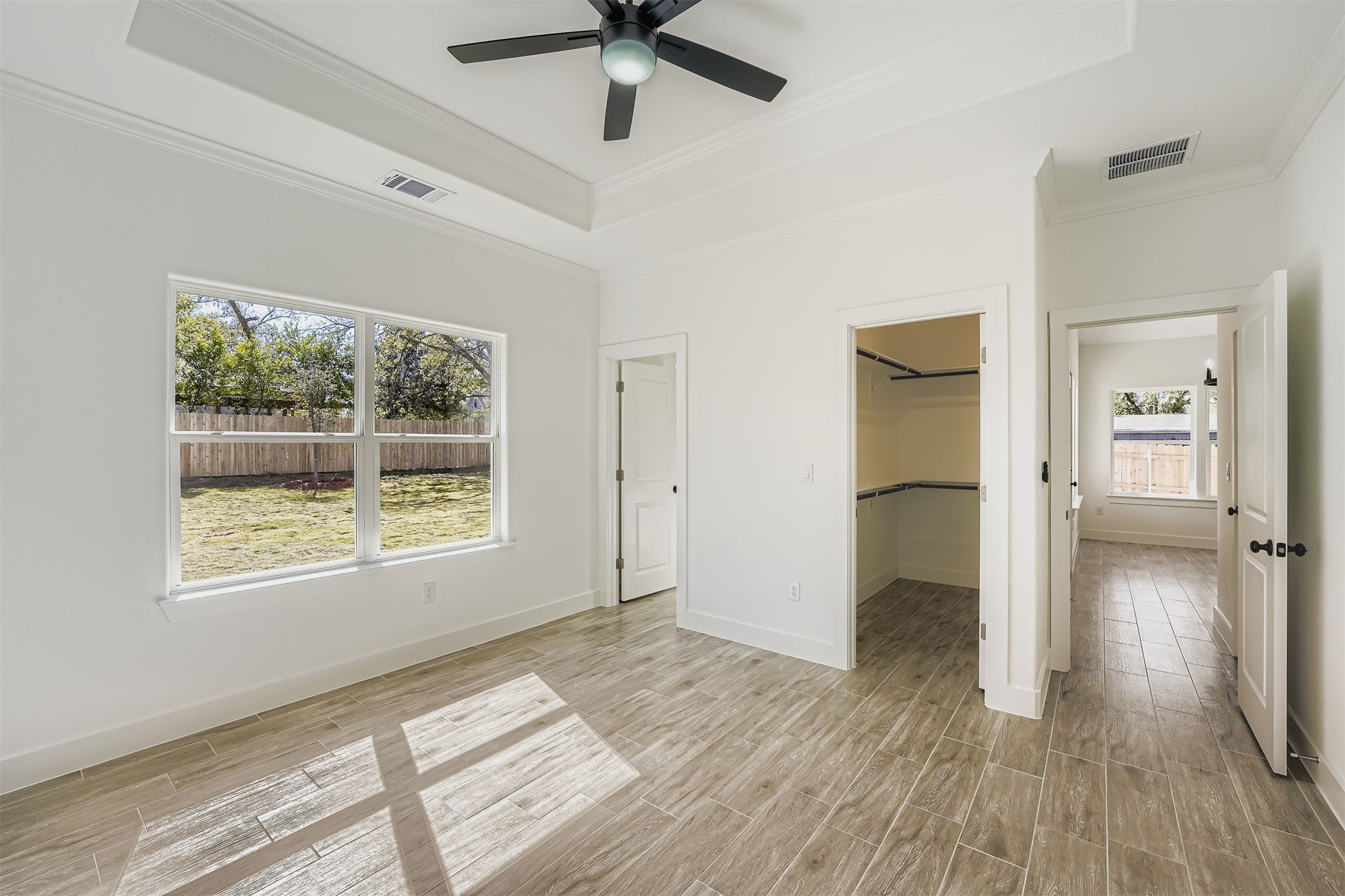 701 East 3rd Street Elgin, TX 78621 - Photo 18 of 35 Spacious primary bedroom with tray ceiling, large window for natural light, and a walk-in closet.
