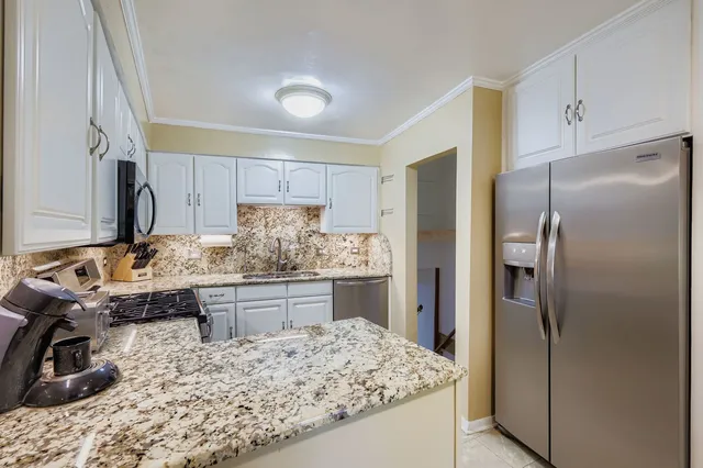 a kitchen with kitchen island granite countertop a refrigerator stove and sink