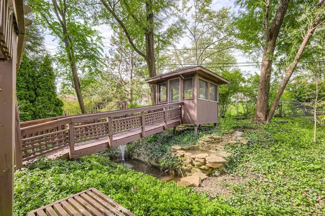 a view of a wooden house with a small yard and large trees
