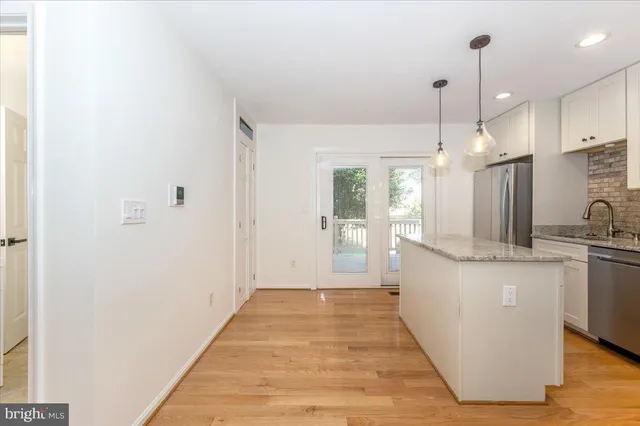 a kitchen with stainless steel appliances granite countertop a refrigerator a stove top oven a sink and dishwasher with wooden floor