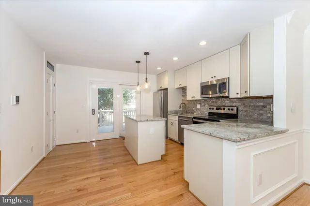 a kitchen with stainless steel appliances granite countertop a refrigerator a stove a sink and a wooden floors