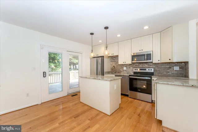 a kitchen with a refrigerator a sink dishwasher a stove and white cabinets with wooden floor