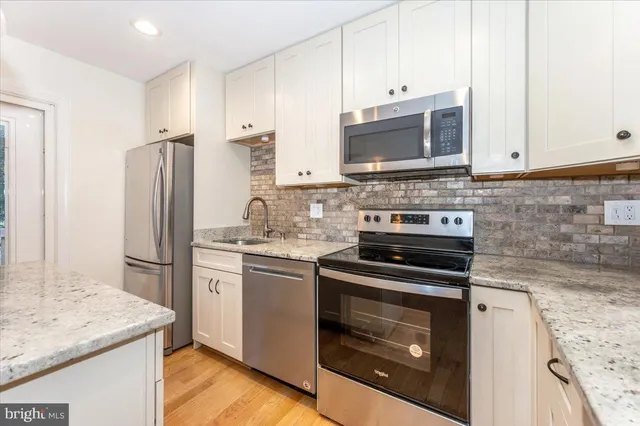 a kitchen with granite countertop cabinets a sink dishwasher and a stove with wooden floor
