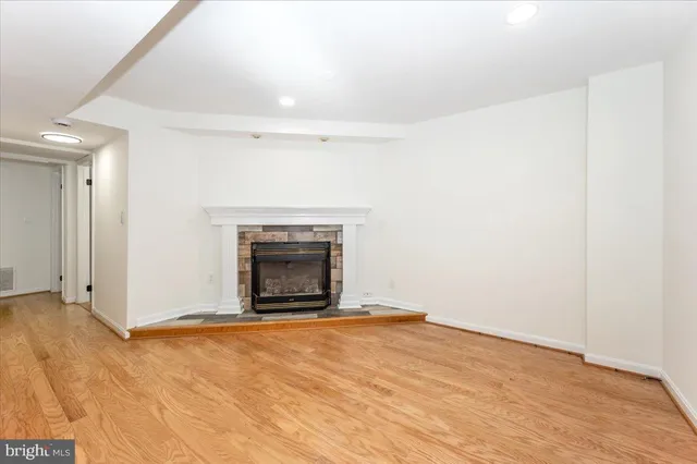a view of empty room with wooden floor and fireplace