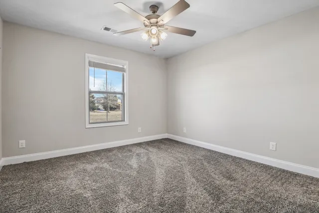 an empty room with a window and a fan