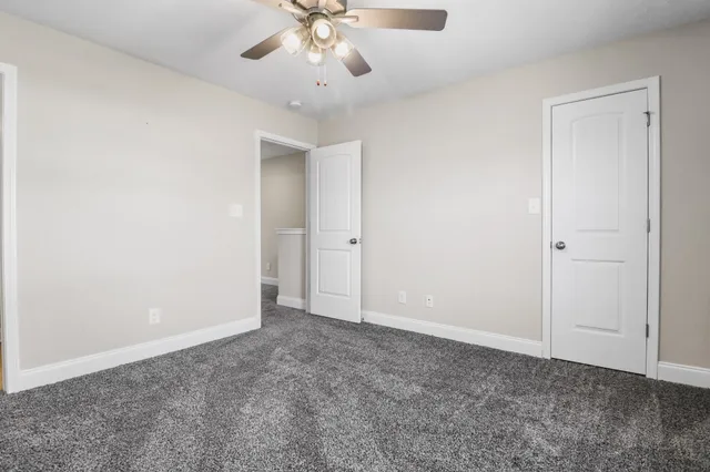 an empty room with a chandelier fan and closet area
