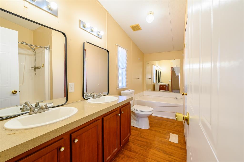 383 Soaring Eagle Trail Wichita Falls, TX 76310 - Photo 16 of 36 Full bathroom with a garden tub, double vanity, a shower with shower curtain, and dark wood-type flooring
