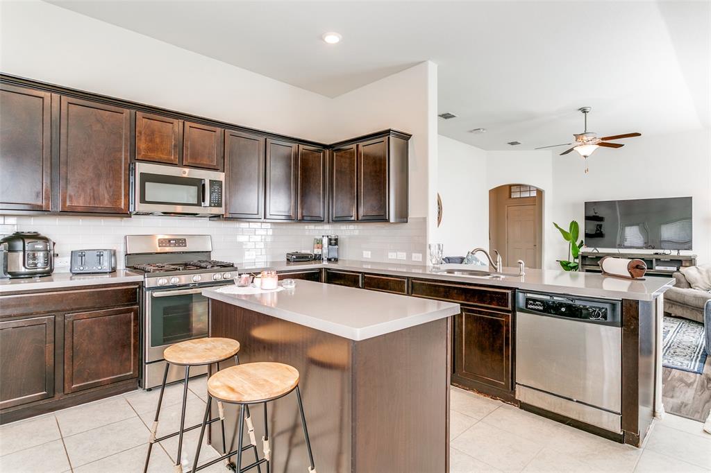 14549 Serrano Ridge Road Fort Worth, TX 76052 - Photo 11 of 25 a kitchen with stainless steel appliances granite countertop a stove top oven a sink dishwasher and white cabinets