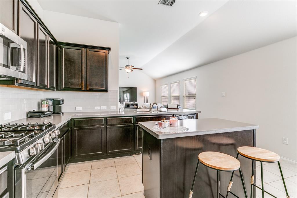 14549 Serrano Ridge Road Fort Worth, TX 76052 - Photo 12 of 25 a kitchen with stainless steel appliances a sink a stove a table and chairs