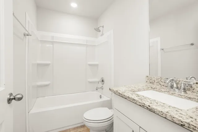a bathroom with a granite countertop sink a toilet and shower