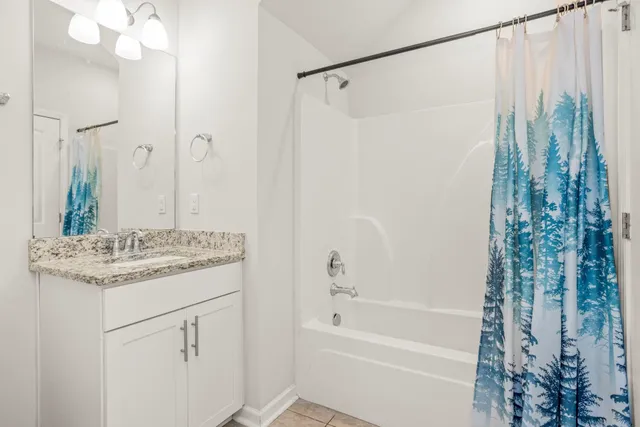 a bathroom with a granite countertop sink a mirror a vanity and a shower