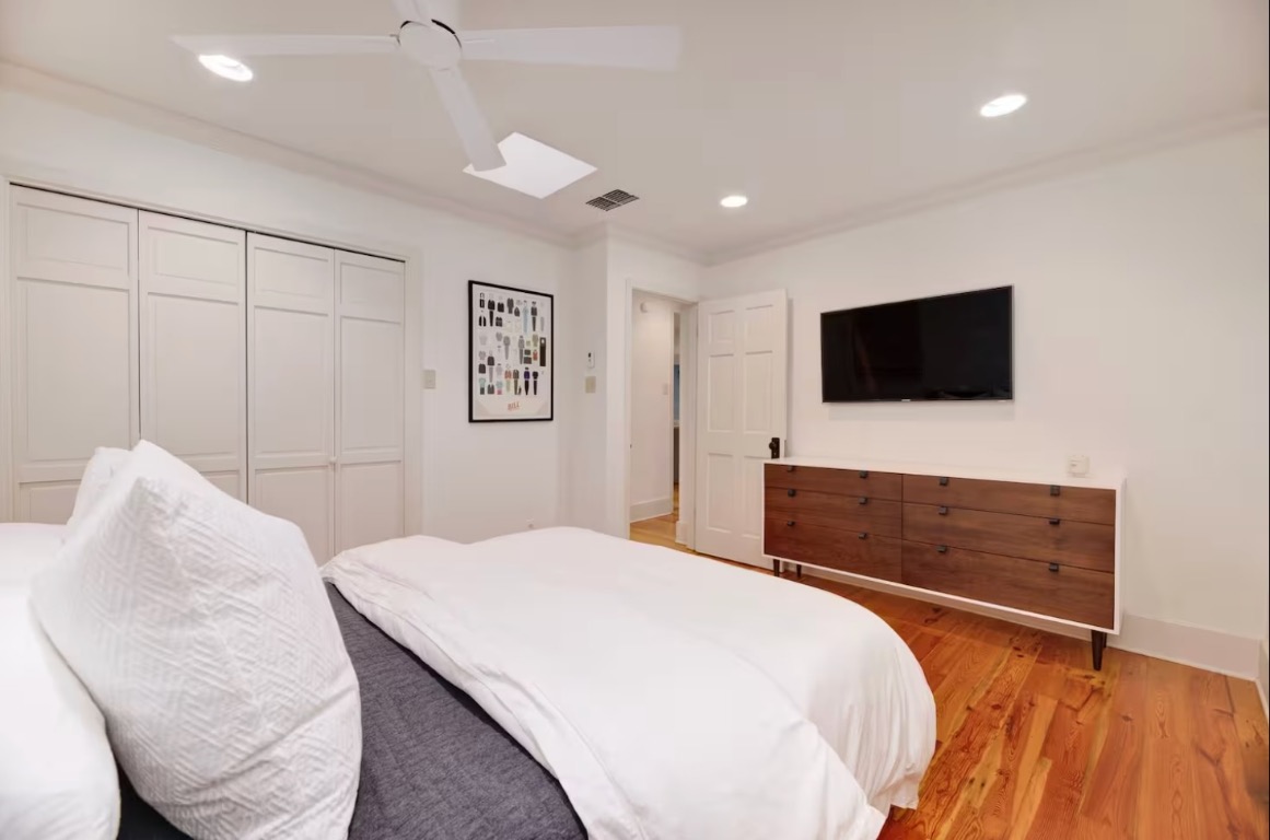 1212 Baylor Street Austin, TX 78703 - Photo 8 of 14 Bedroom with a ceiling fan, crown molding, light wood finished floors, a closet, and recessed lighting