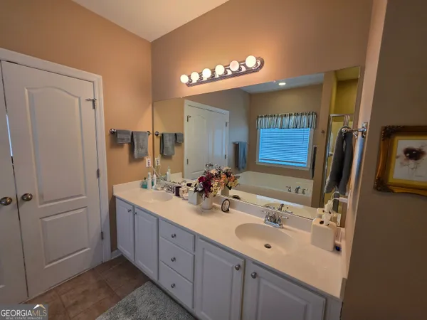 a bathroom with a double vanity sink a mirror and a bathtub