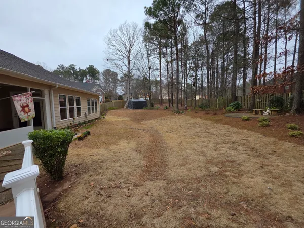 a backyard of a house with large trees and outdoor seating