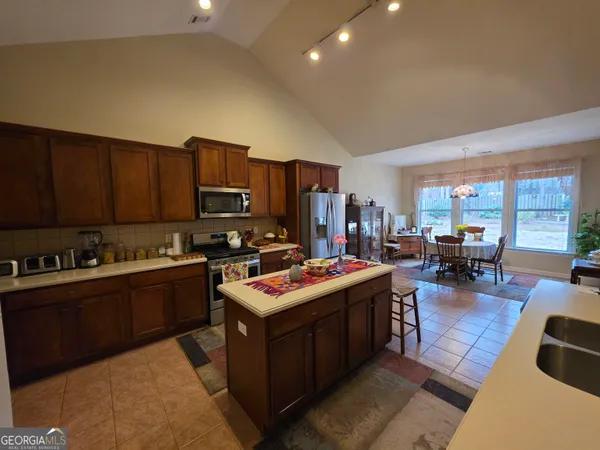 a open kitchen with stainless steel appliances granite countertop a stove top oven a sink dishwasher and cabinets with wooden floor