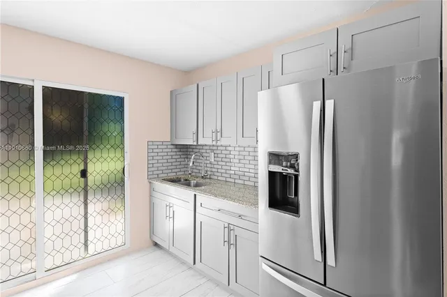 a kitchen with white cabinets and refrigerator