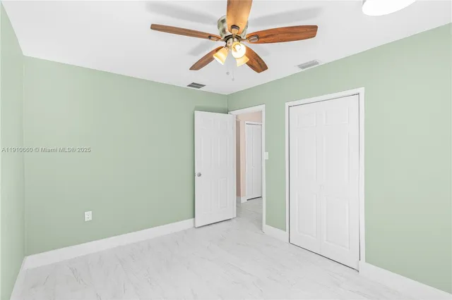 an empty room with windows and fan