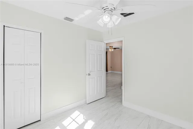 an empty room with a ceiling fan and a window