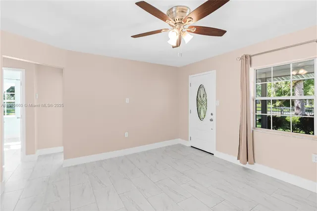 an empty room with windows and fan