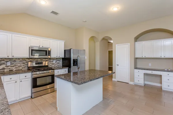 a kitchen with stainless steel appliances granite countertop a stove a sink and a refrigerator