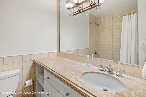 a bathroom with a granite countertop sink a toilet and shower