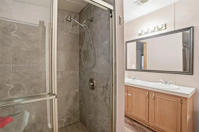 a bathroom with a bathtub shower sink vanity and mirror