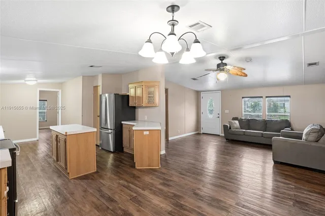 a view of a kitchen with microwave a refrigerator and a view of living room