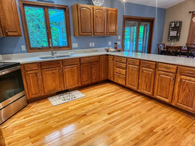 a kitchen with stainless steel appliances granite countertop wooden cabinets a sink and dishwasher a stove with wooden floor