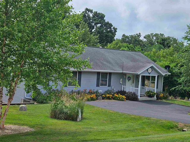 a front view of a house with garden and trees
